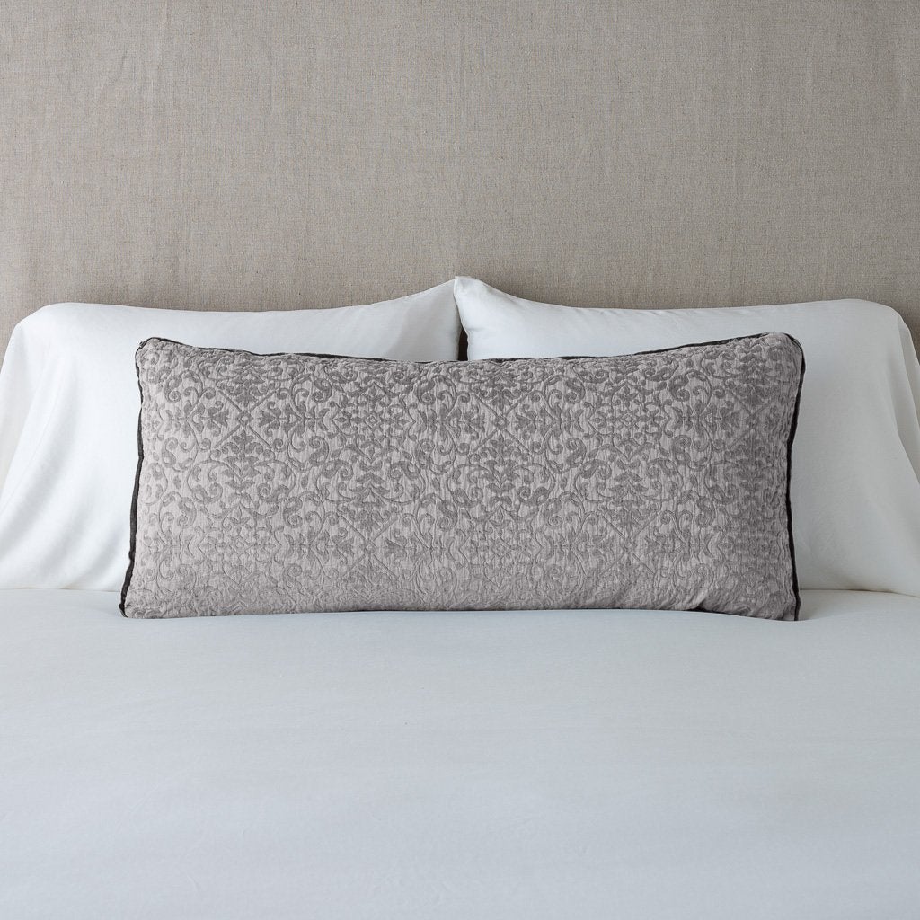 Fog: Vienna 16x36 pillow leaning upright against white sleeping pillows on a neutral headboard - fog.
