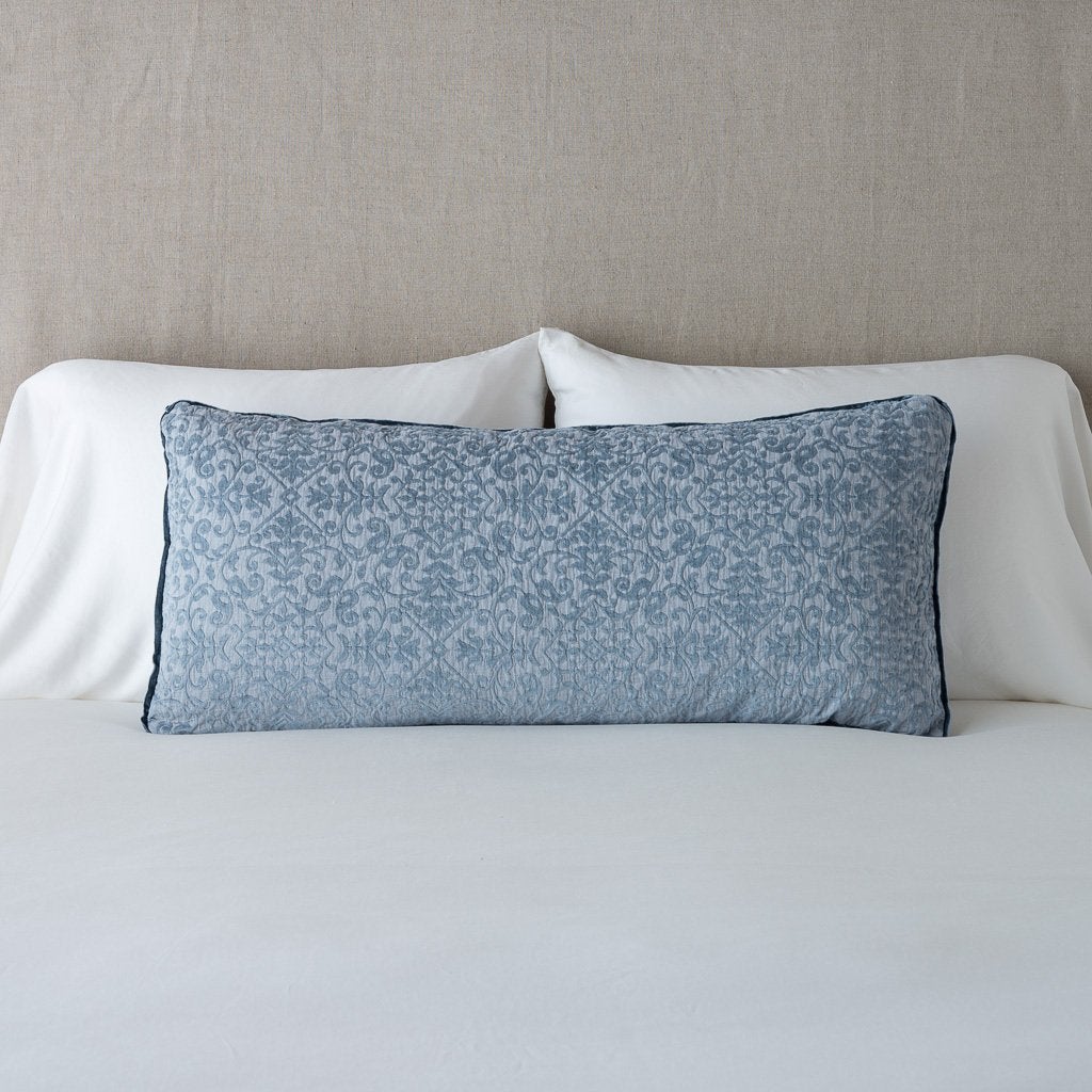 Mineral: Vienna 16x36 pillow leaning upright against white sleeping pillows on a neutral headboard - mineral.