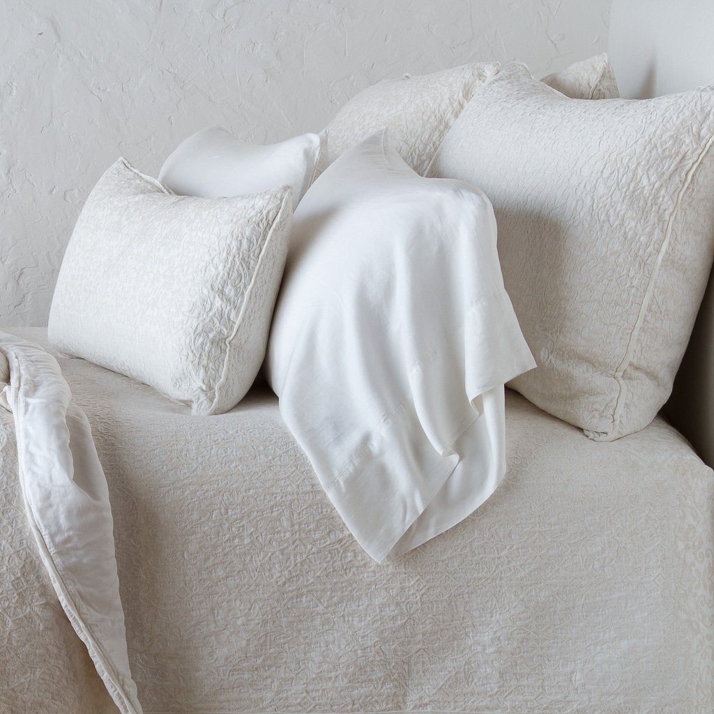 [allvariants]: Vienna shams with matching coverlet and lumbar pillow, and on-tone sleeping pillow - winter white, cropped side view.